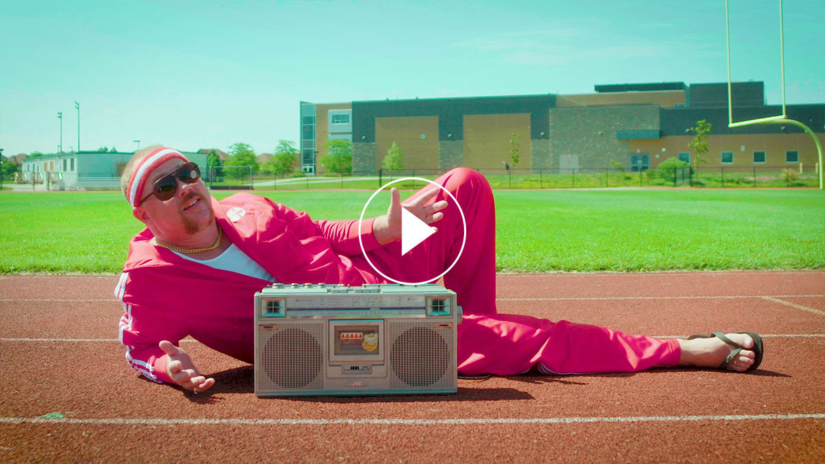 A man in a pink tracksuit lying on the floor behind a cassette player