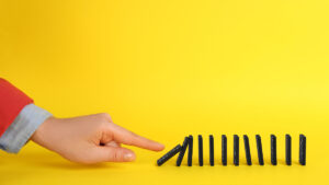 a hand knocking over a line of dominos